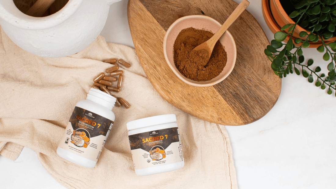 Naturealm Sacred 7 Mushroom Extract Powder and Capsules in kitchen with capsules on towel and brown mushroom powder in a bowl with a wooden spoon